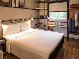 Contemporary hotel room with a minimalist design, featuring a queen-sized bed and a large window